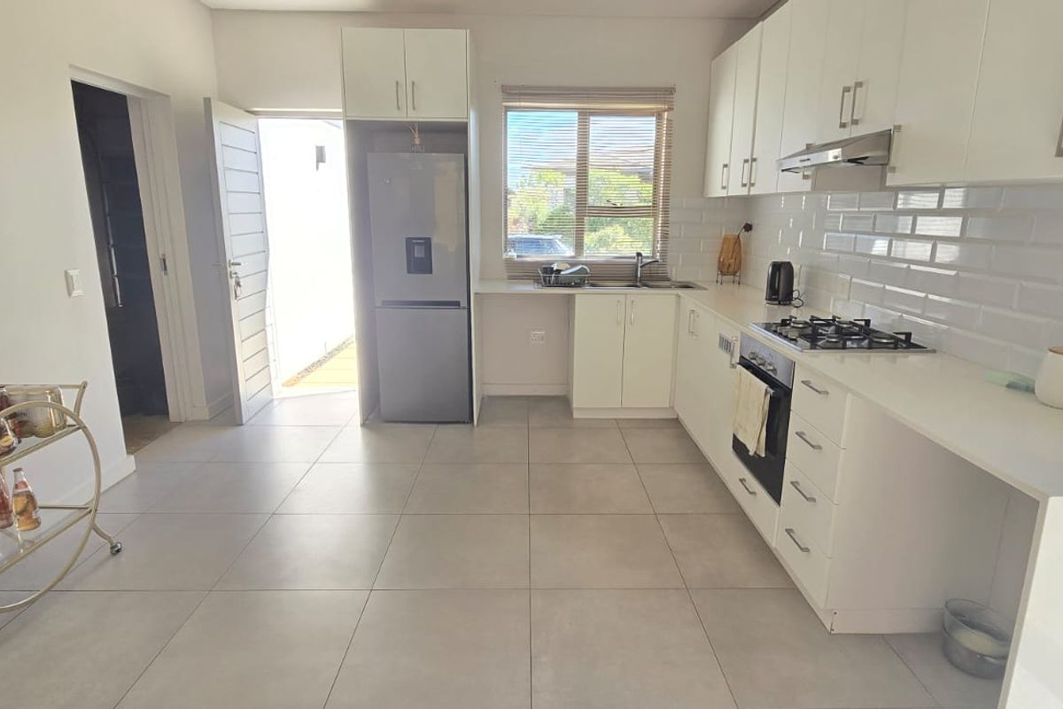 Modern kitchen featuring white cabinetry, subway tile backsplash, gas hob, built-in oven, and tiled flooring with direct access to the exterior.