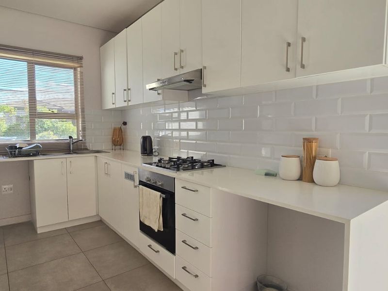 Modern kitchen featuring white cabinetry, subway tile backsplash, gas hob, built-in oven, and tiled flooring with ample counter space.
