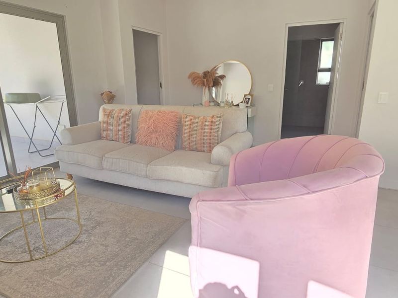A bright living room featuring large sliding glass doors that provide natural light and access to the outdoor area, finished with neutral floor tiles.