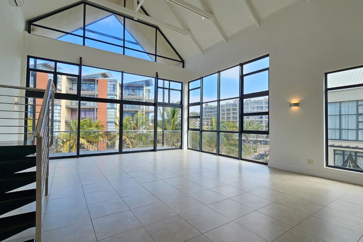Spacious, light-filled living area featuring a vaulted ceiling, large windows with expansive views, and a modern staircase with metal balustrades.