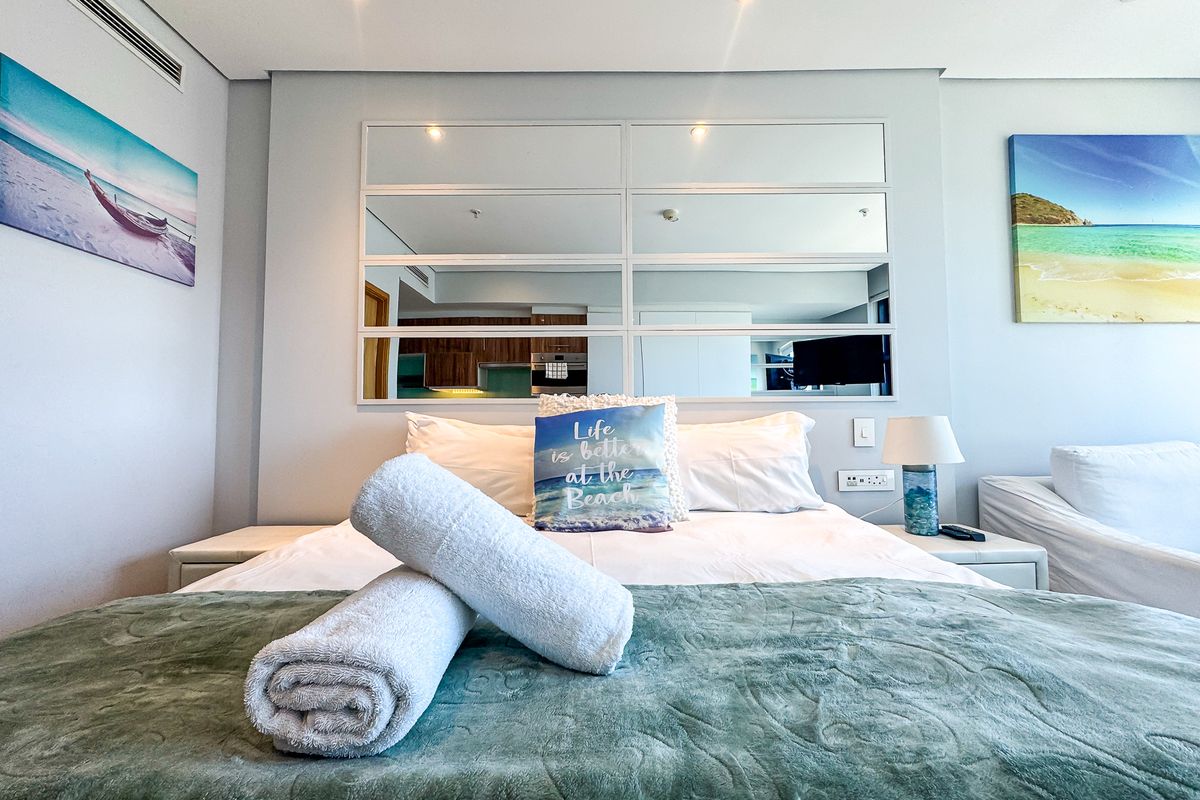 A well-maintained bedroom featuring a central mirrored wall panel, recessed downlighting, and integrated ducted air conditioning.