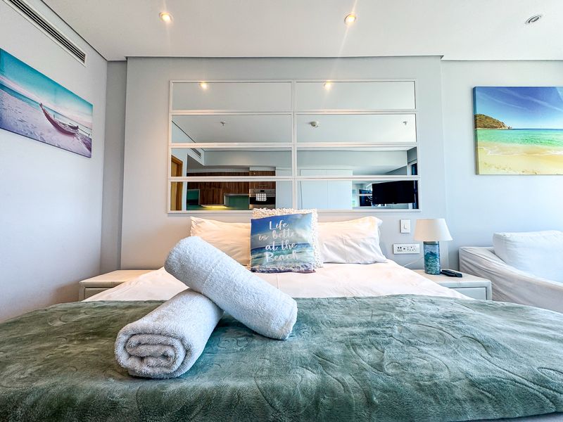 A well-maintained bedroom featuring a central mirrored wall panel, recessed downlighting, and integrated ducted air conditioning.