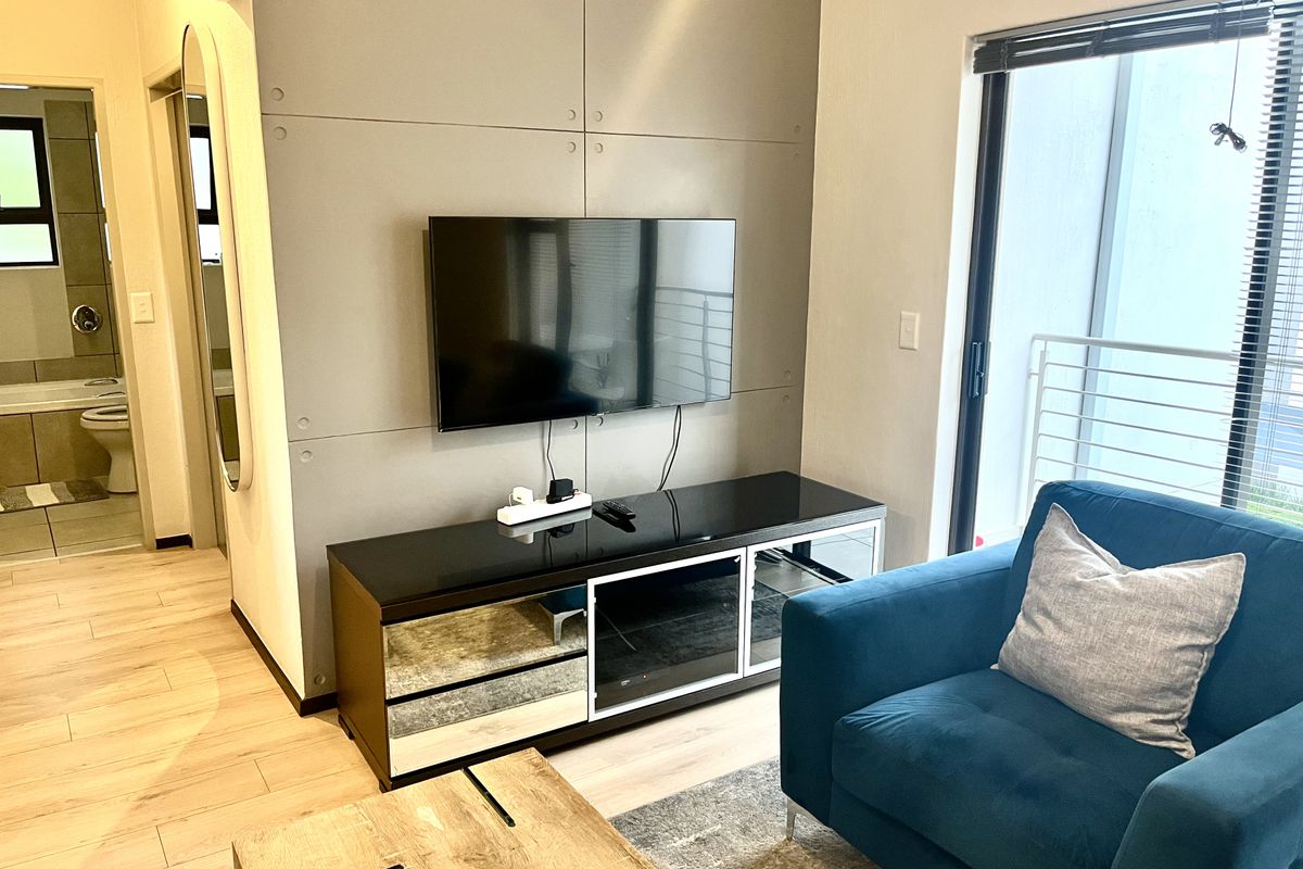 A modern living room featuring a feature wall, laminate flooring, and a sliding glass door leading to an outdoor area.