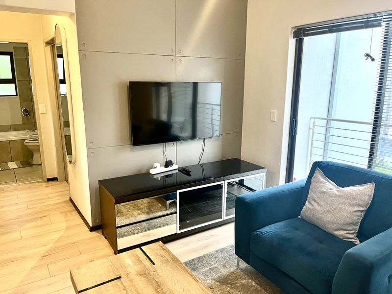 A modern living room featuring a feature wall, laminate flooring, and a sliding glass door leading to an outdoor area.