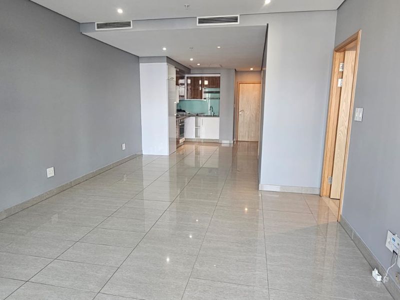 Spacious open-plan living area featuring modern porcelain tiling, recessed lighting, ducted air conditioning, and a sleek, integrated kitchen layout.