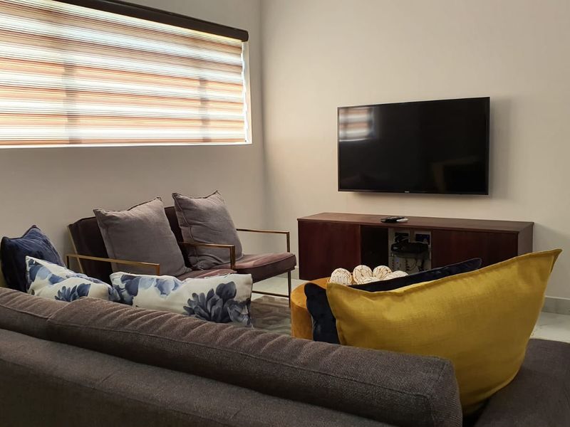 A well-maintained living room featuring tiled flooring, neutral walls, and modern roller blinds, providing a clean and comfortable space.