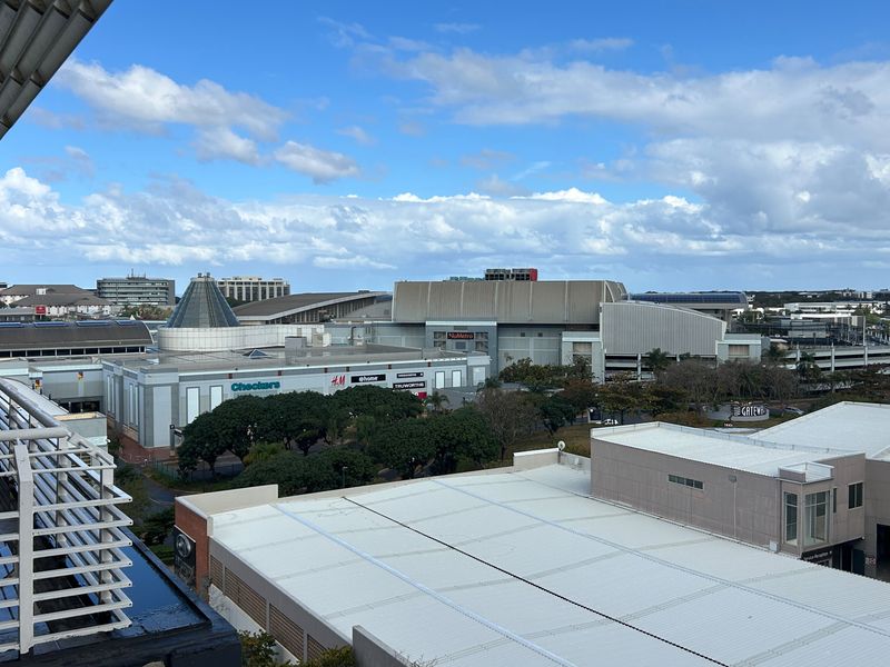 Elevated urban view overlooking a shopping center and surrounding commercial area from a private balcony.