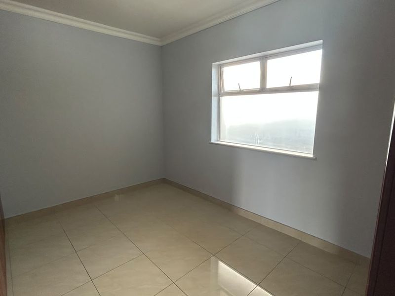 A clean, empty bedroom featuring neutral tiled flooring, built-in cupboards, and classic ceiling cornicing, offering a blank canvas for personalization.