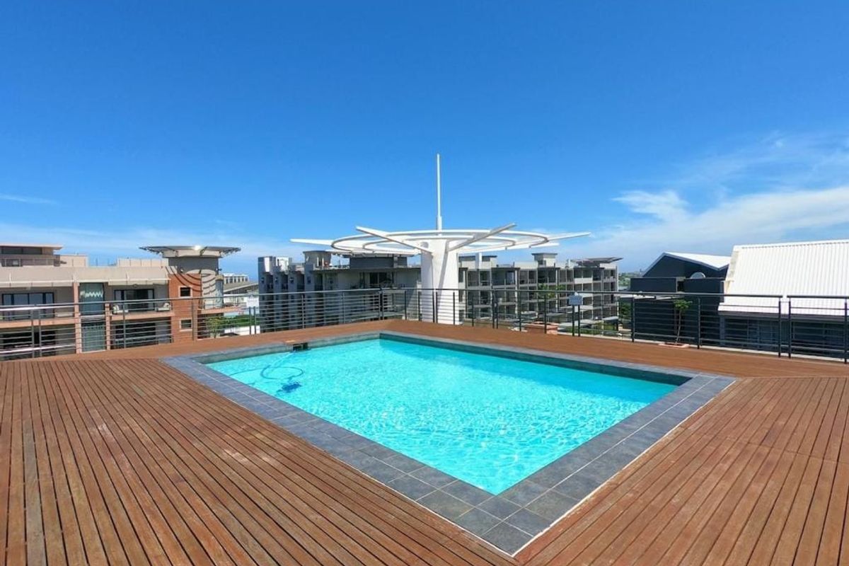 A rooftop swimming pool featuring timber decking and modern metal balustrades, offering an open-air leisure space with clear views.