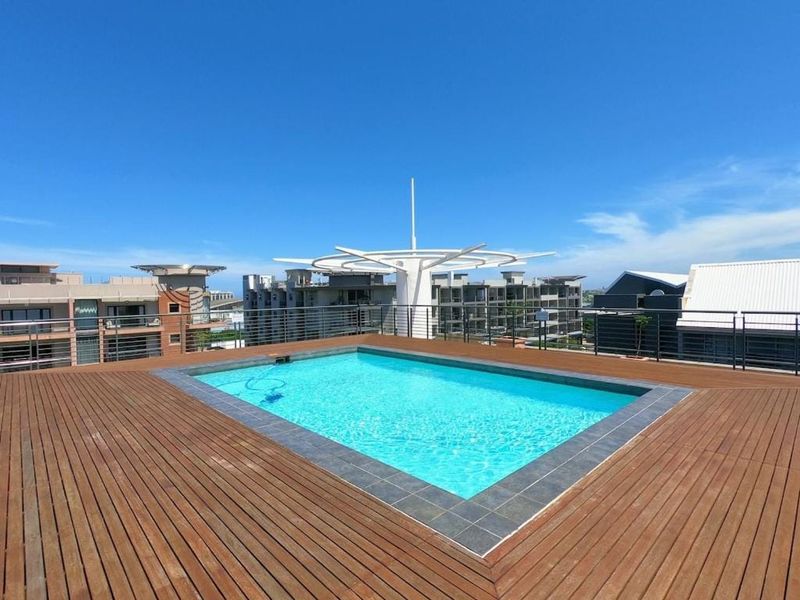 A rooftop swimming pool featuring timber decking and modern metal balustrades, offering an open-air leisure space with clear views.