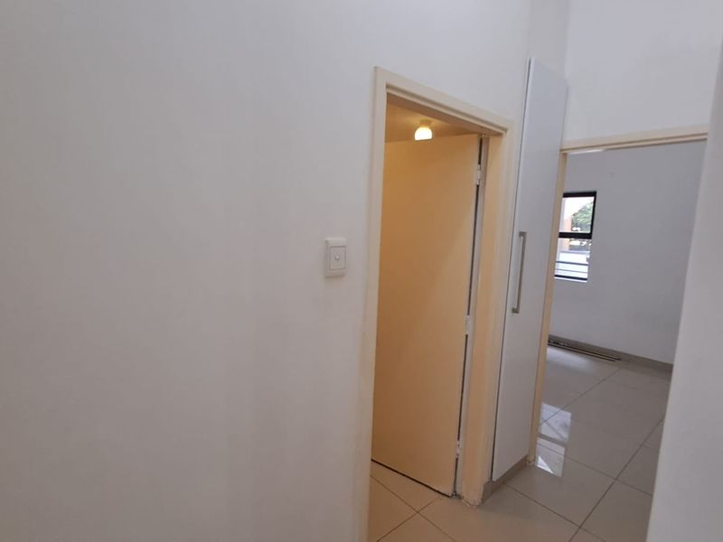 A bright, empty hallway featuring tiled flooring and built-in storage, providing access to adjacent rooms within the apartment.