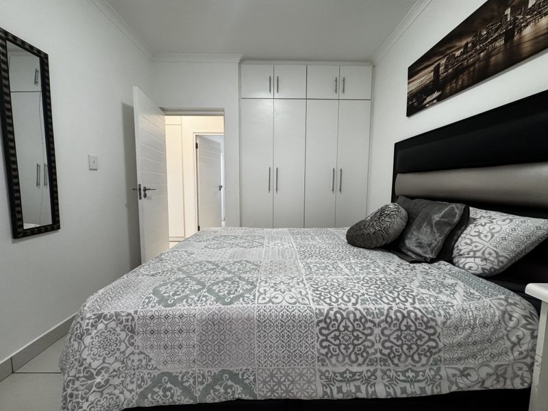 A well-maintained bedroom featuring built-in cupboards, tiled flooring, and neutral finishes, offering a clean and functional living space.