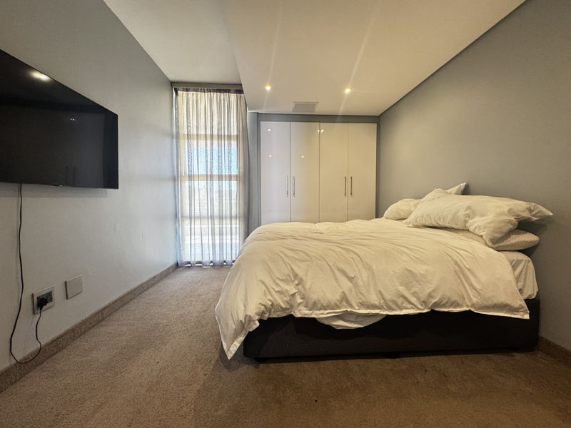 A well-lit bedroom featuring built-in wardrobes, neutral wall tones, and carpet flooring, providing a comfortable and functional living space.