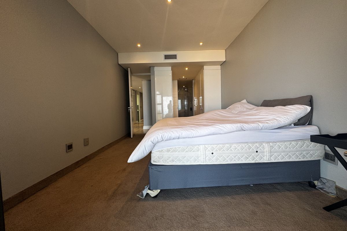A bedroom featuring neutral walls, recessed downlighting, built-in cupboards, and an en-suite bathroom access point.