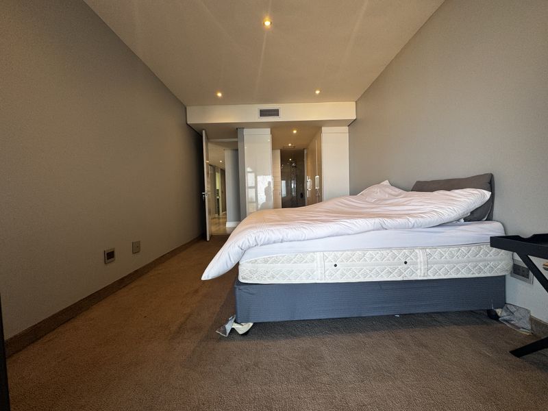 A bedroom featuring neutral walls, recessed downlighting, built-in cupboards, and an en-suite bathroom access point.
