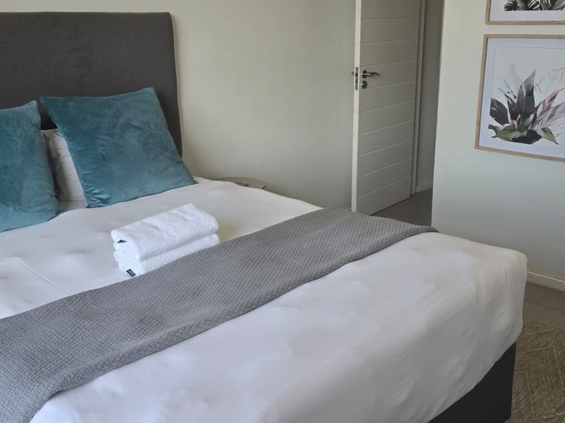 A well-maintained bedroom featuring neutral tiled flooring and a clean, modern interior door leading to an adjacent space.
