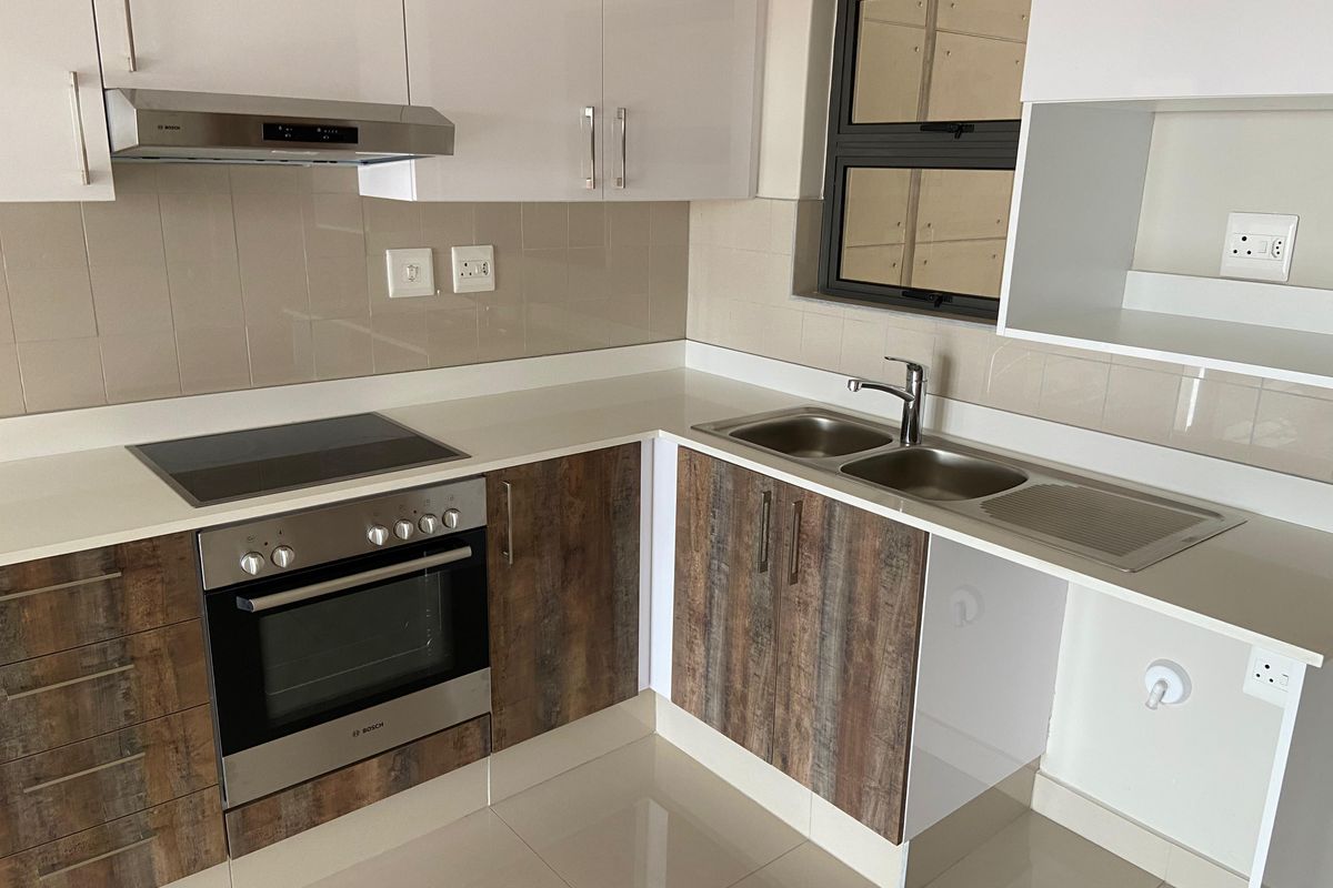Modern kitchen featuring sleek white and wood-grain cabinetry, stone countertops, integrated Bosch oven and hob, and a double sink with tiled splashback.
