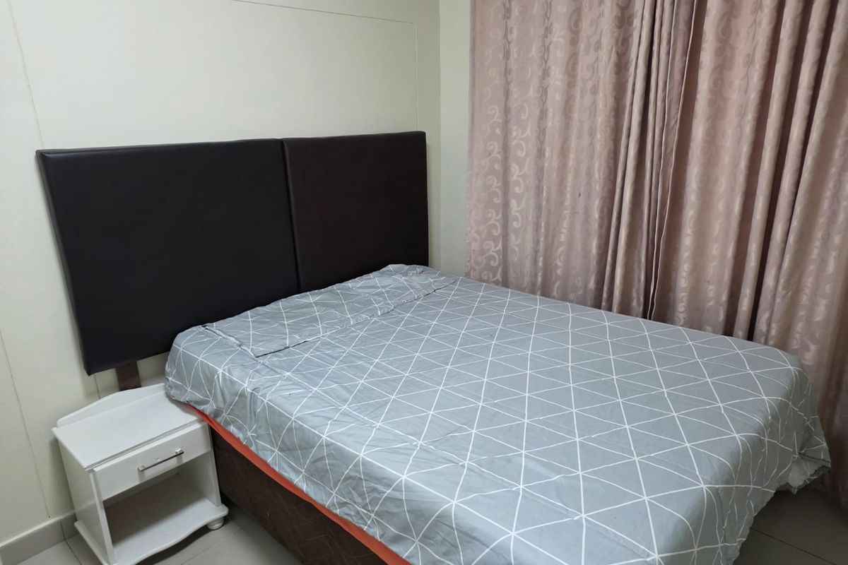 A functional bedroom featuring tiled flooring and neutral wall finishes, providing a simple and clean space for rest.