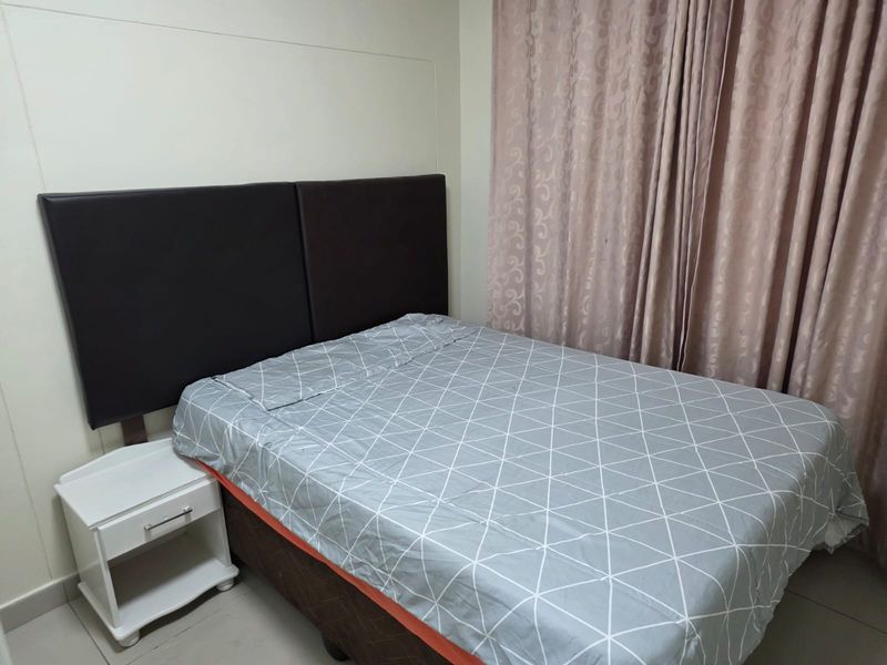 A functional bedroom featuring tiled flooring and neutral wall finishes, providing a simple and clean space for rest.