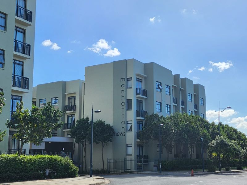 Exterior view of the Manhattan Mews apartment complex, featuring modern multi-story architecture with balconies and landscaped surroundings.