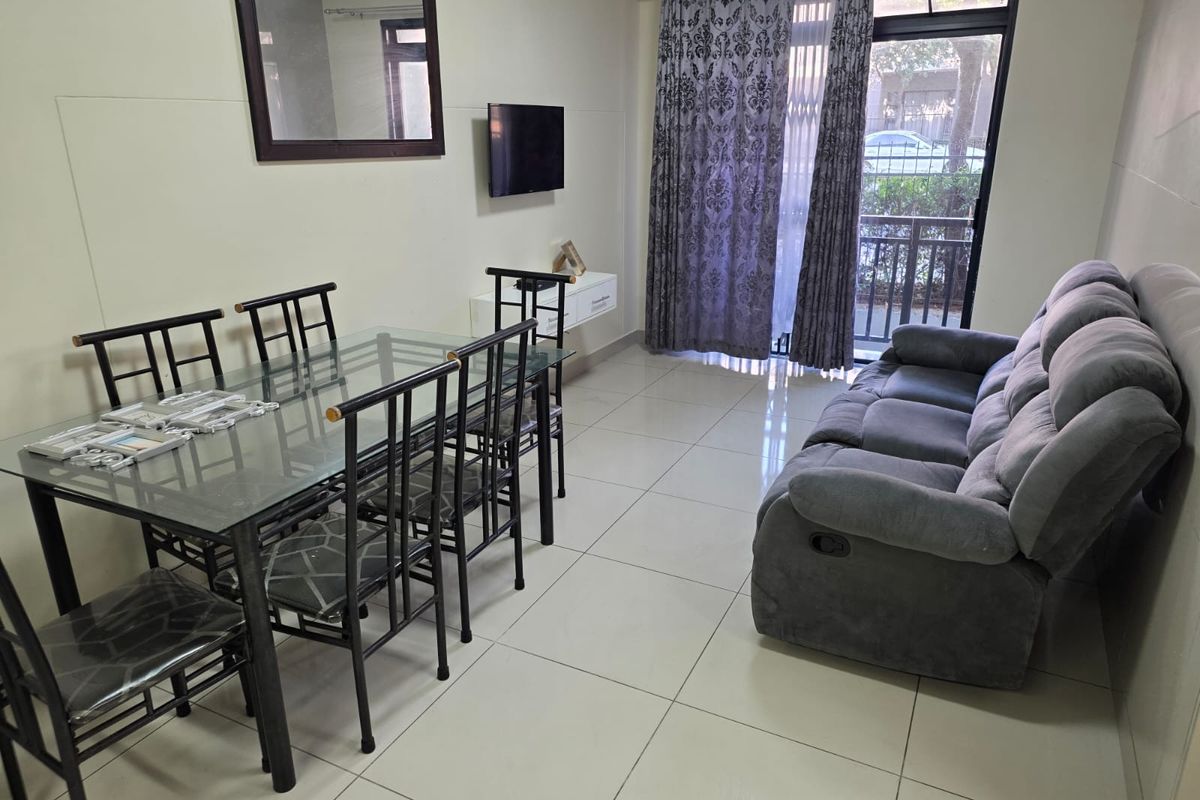 A living and dining area featuring large format floor tiles, a sliding glass door with security gate, and access to an outdoor space.