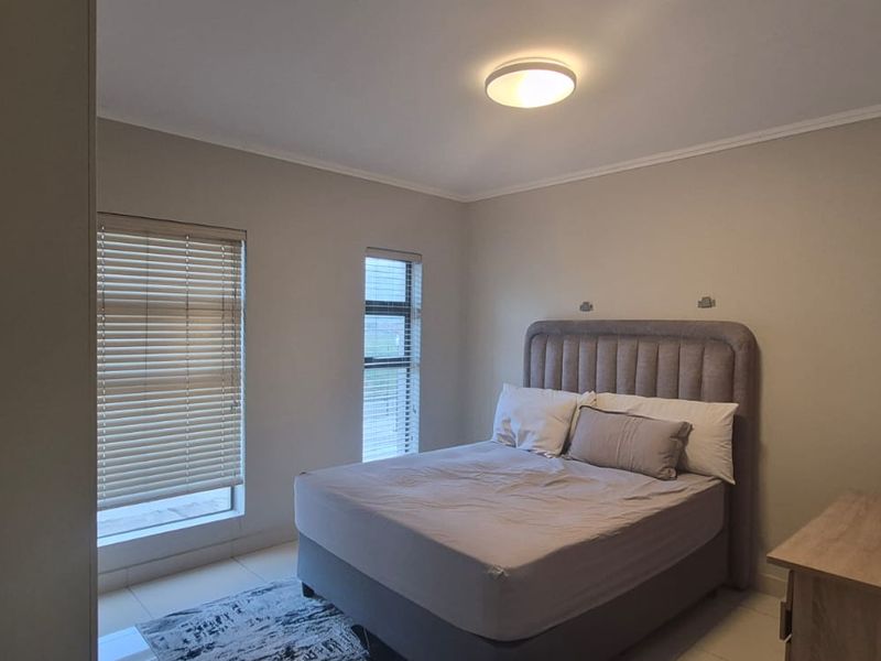 A well-maintained bedroom featuring neutral wall tones, tiled flooring, and venetian blinds, providing a clean and functional living space.