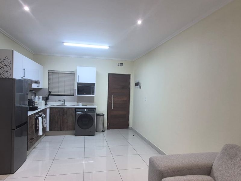 An open-plan kitchen and living area featuring modern cabinetry, tiled flooring, and recessed lighting, providing a functional and well-lit space.