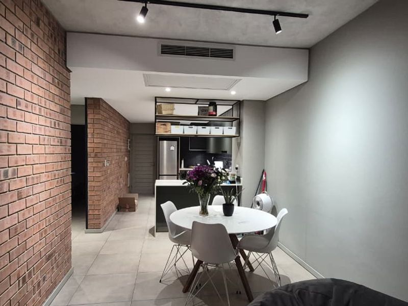Modern open-plan living and dining area featuring an exposed brick feature wall, tiled flooring, and integrated kitchen cabinetry with recessed lighting.