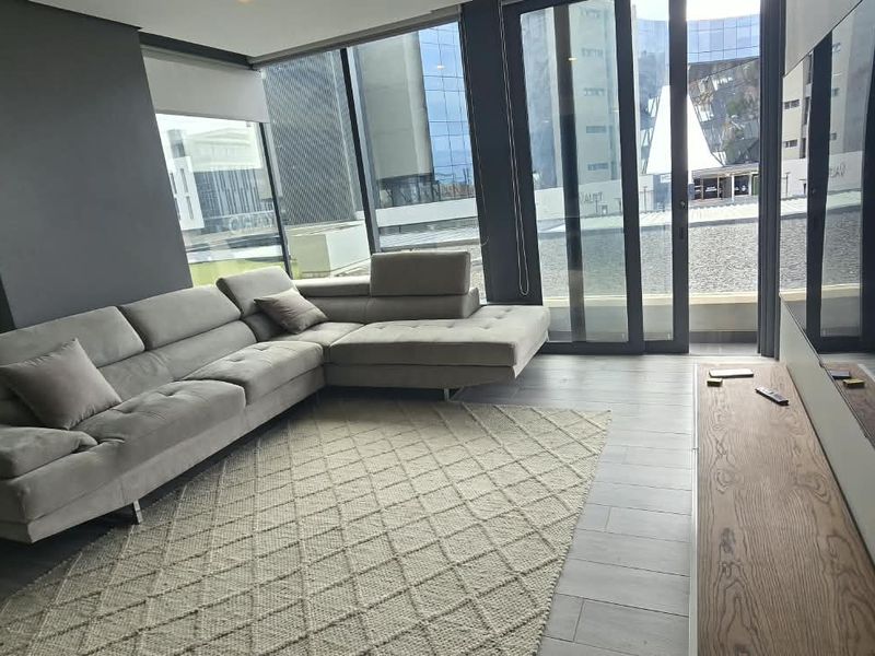 Modern living room featuring large format floor tiles, floor-to-ceiling windows, and sliding glass doors providing ample natural light and access to the exterior.