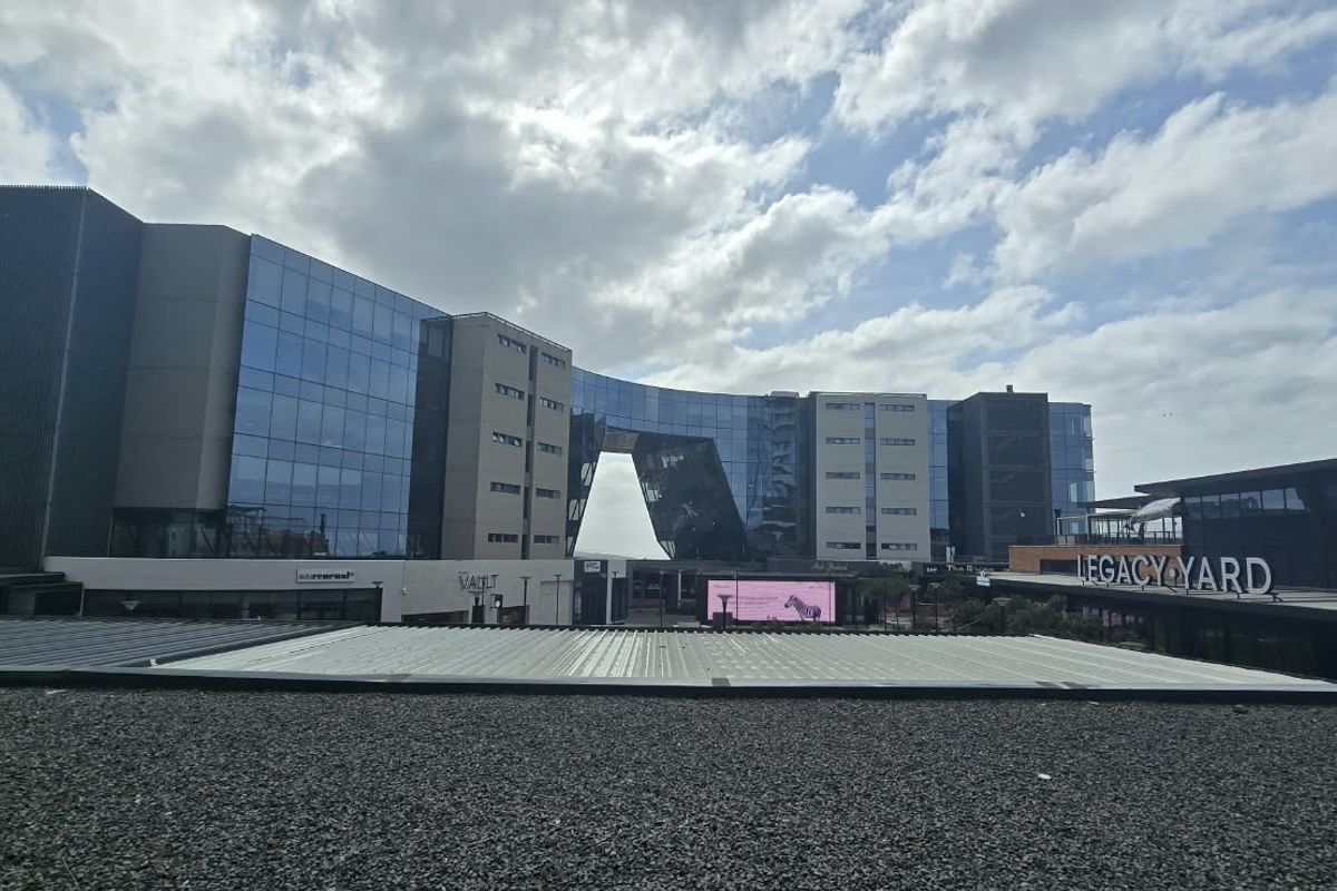 Exterior view of a modern commercial and residential building complex featuring glass facades and metal roofing.