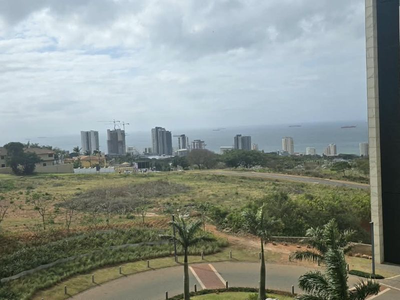 An elevated view overlooking the surrounding neighbourhood, coastal landscape, and distant city skyline from the apartment balcony.