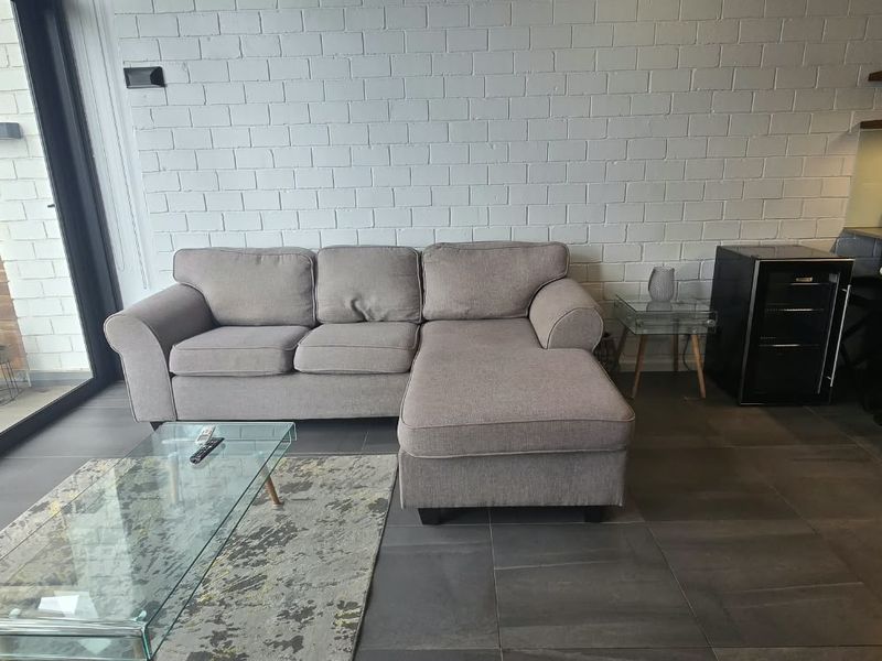 Modern open-plan living area featuring a textured brick feature wall, large sliding doors to the balcony, and a sleek kitchen with floating shelving.