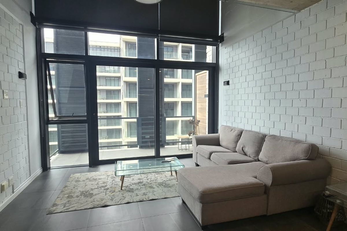 Modern living room featuring exposed white brick walls, large floor-to-ceiling windows with roller blinds, and tiled flooring, providing access to a balcony.