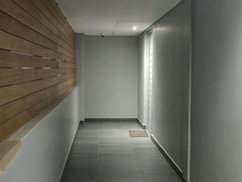 A clean, modern hallway featuring contemporary grey floor tiles and decorative timber wall cladding, providing a sleek and well-maintained transition space.