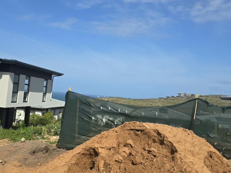 View of a modern residential property under construction, featuring coastal views and an unlandscaped rear yard area.