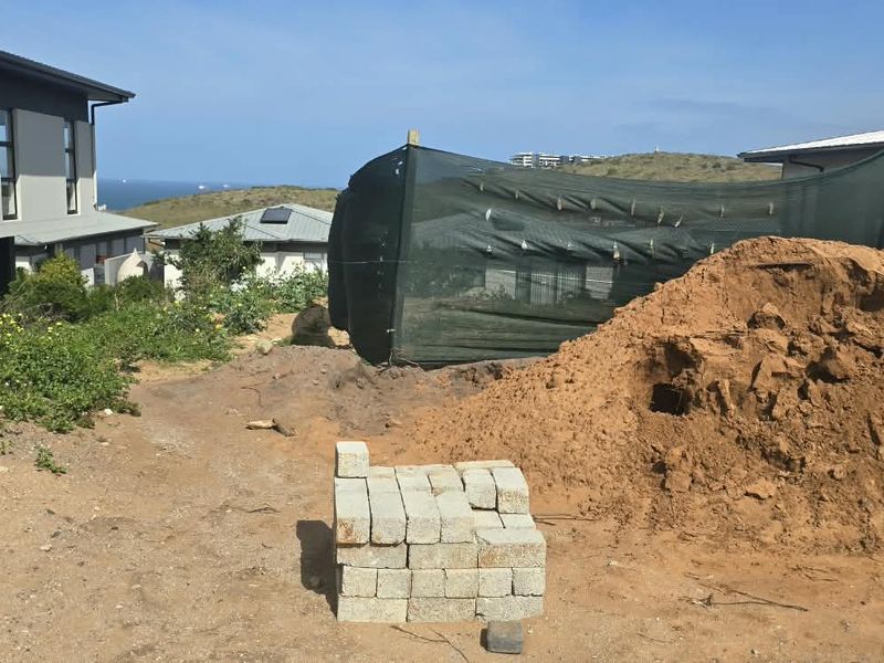 Vacant residential land plot showing ongoing site preparation, construction materials, and temporary fencing with surrounding neighborhood views.