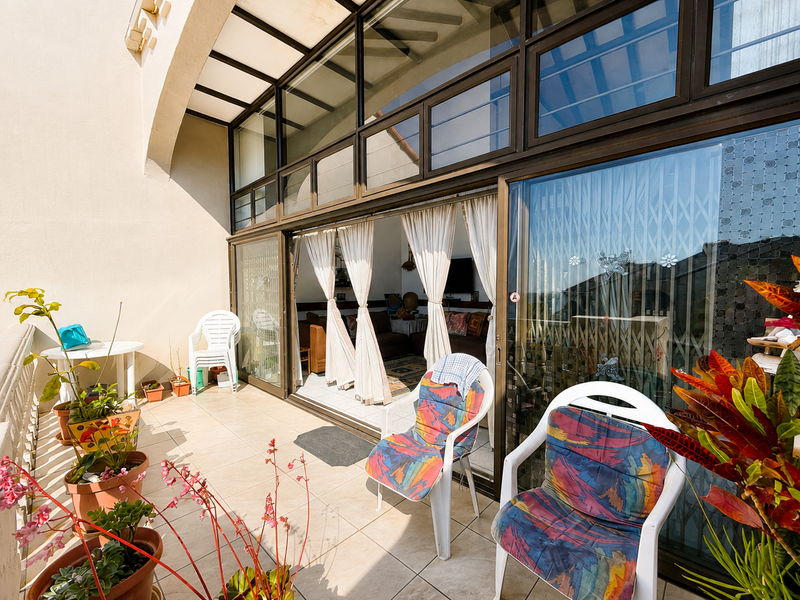 A covered balcony featuring tiled flooring and large sliding glass doors that provide access to the interior living space.