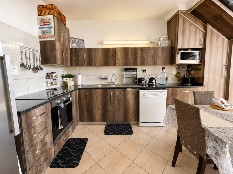 A functional kitchen featuring wood-look laminate cabinetry, granite countertops, a built-in oven, and a ceramic hob with a tiled backsplash.