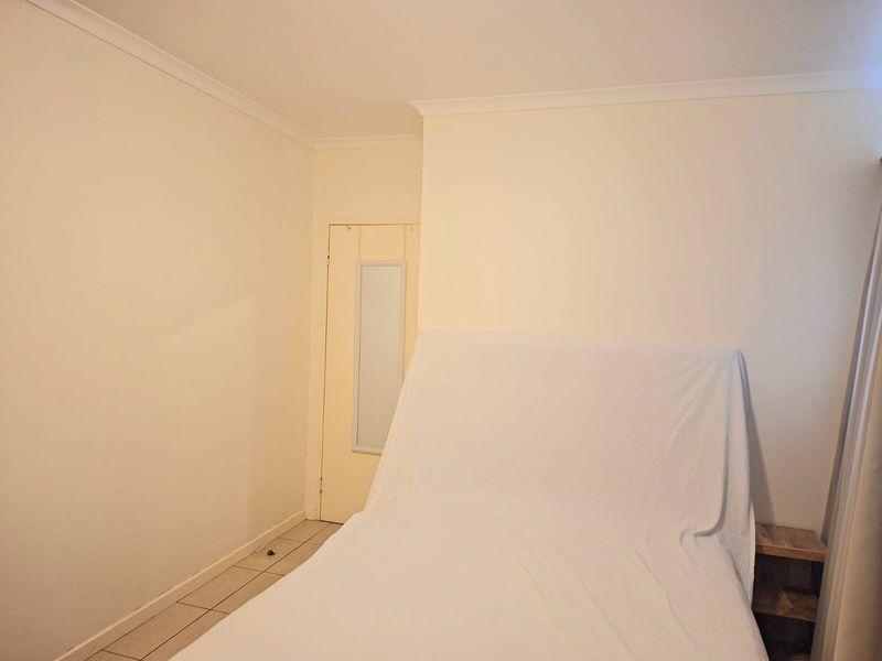 A simple bedroom featuring tiled flooring and neutral walls, providing a clean and functional space ready for personalization.