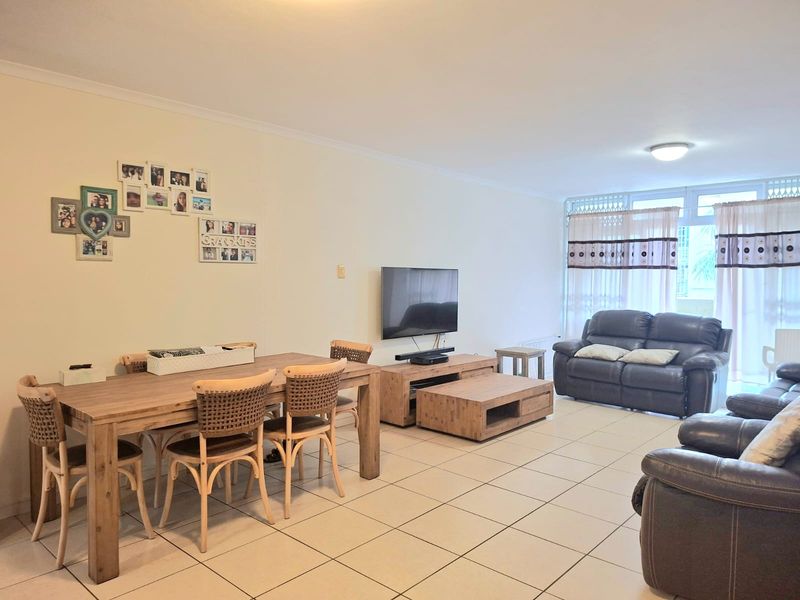 Spacious open-plan living and dining area featuring neutral tiled flooring and large sliding glass doors providing natural light.