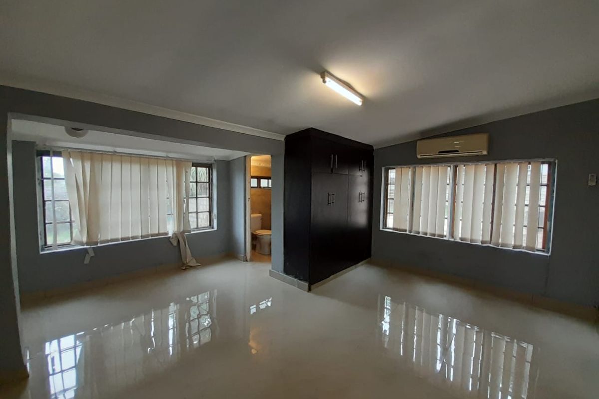 Spacious bedroom featuring tiled flooring, built-in wardrobe, air conditioning unit, and direct access to an en-suite bathroom.