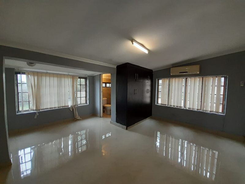 Spacious bedroom featuring tiled flooring, built-in wardrobe, air conditioning unit, and direct access to an en-suite bathroom.