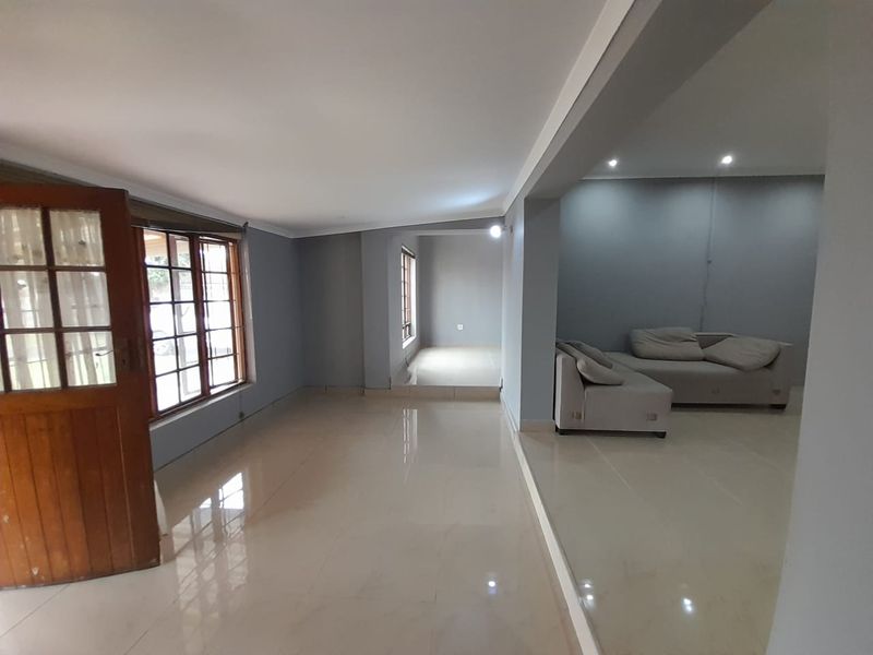 Spacious open-plan living area featuring polished tiled flooring, split-level design, and timber-framed windows, offering a versatile layout for modern living.