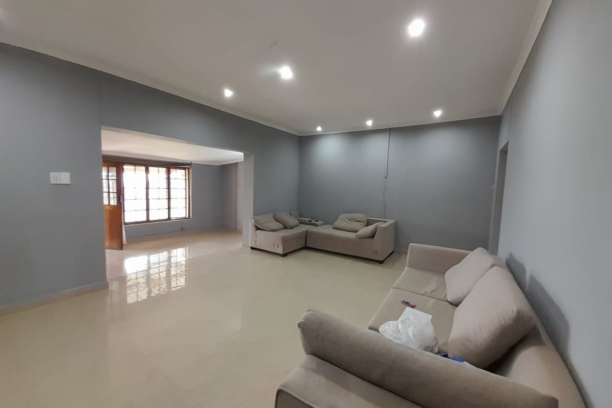 A spacious living area featuring neutral grey walls, polished tiled flooring, and recessed downlighting, offering a clean and versatile space for relaxation.