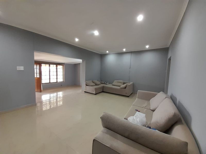 A spacious living area featuring neutral grey walls, polished tiled flooring, and recessed downlighting, offering a clean and versatile space for relaxation.