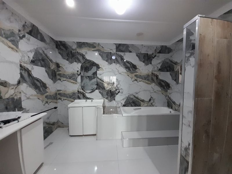 A modern bathroom featuring striking marble-effect wall tiling, a built-in bathtub, and a clean vanity unit with a basin.