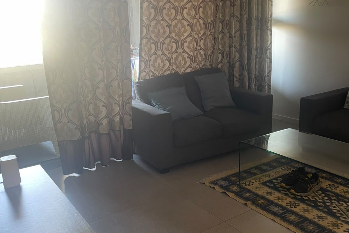 A living room area featuring large format floor tiles and a sliding glass door leading to an outdoor space, with natural light exposure.