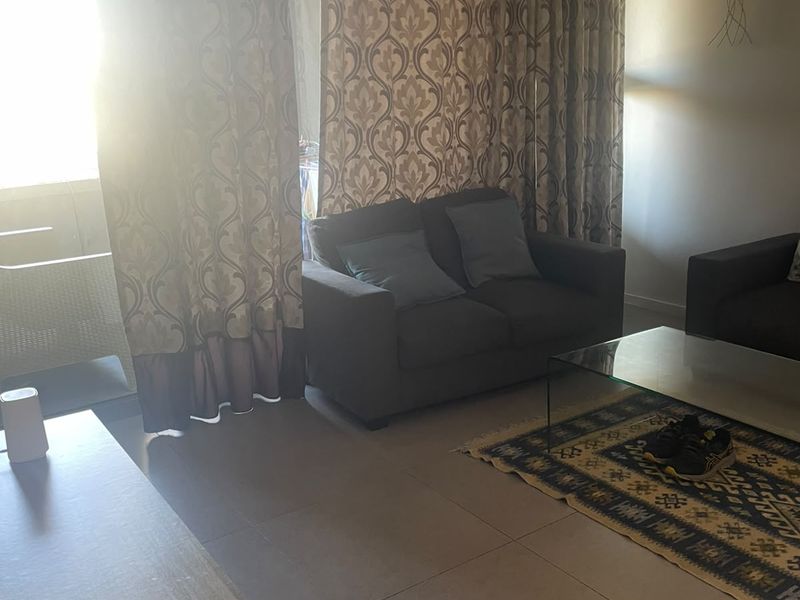 A living room area featuring large format floor tiles and a sliding glass door leading to an outdoor space, with natural light exposure.