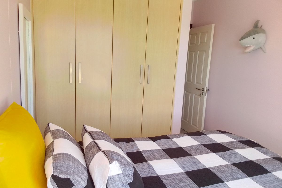 A bedroom featuring light wood-finish built-in cupboards and a classic panel door, providing functional storage and access.