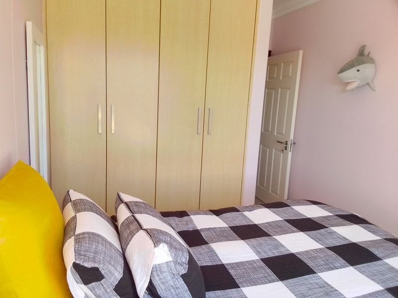 A bedroom featuring light wood-finish built-in cupboards and a classic panel door, providing functional storage and access.